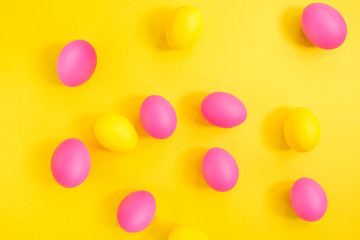 The creative layout of eggs is colored in yellow and pink colors on a yellow background