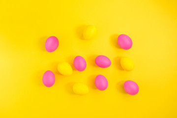 The creative layout of eggs is colored in yellow and pink colors on a yellow background
