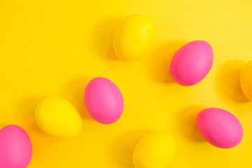 The creative layout of eggs is colored in yellow and pink colors on a yellow background