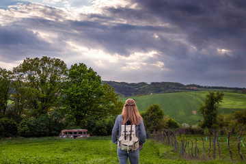 Hiking woman is enjoying view to spring landscape with dramatic sky