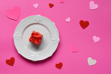 Empty pink plate, felt hearts and red gift on pink background. St. Valentine's Day concept. Top view, flat lay. Copy space