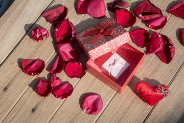 Lovely Gift box with Rose Petals on wooden background for Valentines day