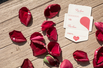 Valentine's Day greeting card. Top view on romantic composition, Short note paper with Rose petals on wooden background for Valentines Day