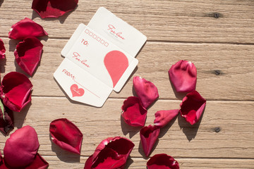 Valentine's Day greeting card. Top view on romantic composition, Short note paper with Rose petals on wooden background for Valentines Day