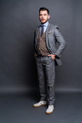 Obraz premium Full length portrait of a fashion male model over grey background. Looking at camera.