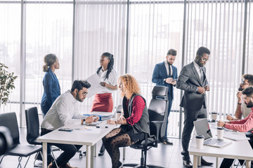 Multiracial group of young diverse students talking, interacting on their workplaces, business...