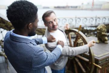 Two young intercultural business leaders fighting for sailing wheel on ship during motion