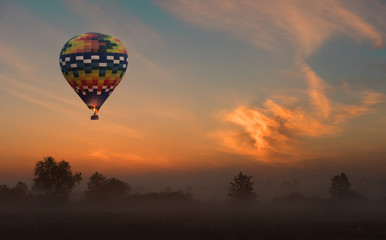 Naklejka premium hot air balloon flying at yellow sunrise.