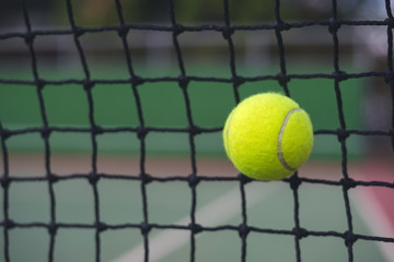 Close up tennis ball hitting to the net on court background with copy space