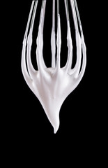 Metal whisk with whipped egg whites, isolated on black background. Clipping path.