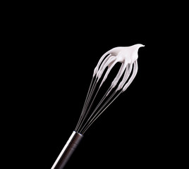 Metal whisk with whipped egg whites, isolated on black background. Clipping path.
