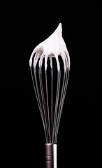 Metal whisk with whipped egg whites, isolated on black background. Clipping path.