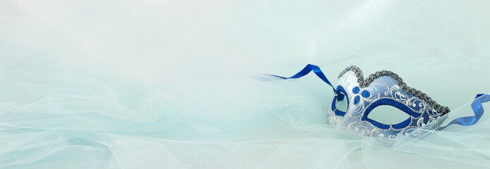 Banner of elegant and delicate silver and blue venetian mask over mint chiffon background.