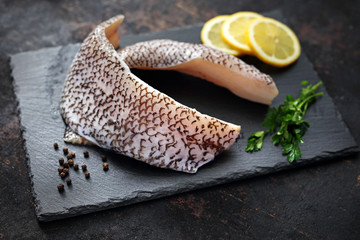 Świeży filet z grenadiera. Surowa ryba na czarnym kamieniu i ciemnym tle. © foodandcook