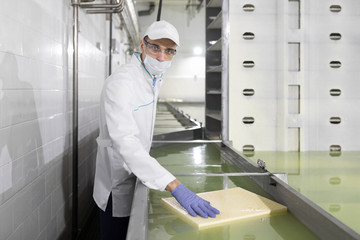 technologist put his hand on a piece of butter at the dairy plant