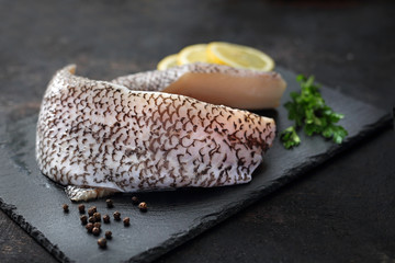 Grenadier. Surowa ryba na czarnym kamieniu i ciemnym tle. © foodandcook