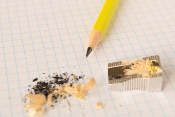 A simple pencil and sharpener on a clean sheet of paper. Close up.
