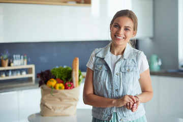 Young woman holding grocery shopping bag with vegetables .Standing in the kitchen