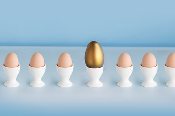 One golden egg and other normal eggs on blue background.