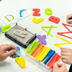 Therapist helping teenage girl with learning difficulties during child therapy. Top view hand detail of a therapist with patient.