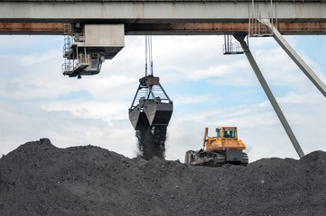 caterpillar tractor and travelling crane load black coal on supply field of thermoelectric power station