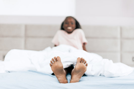 happy cheerful girl lying in the bed and showing her nacked feet. close up photo. funny legs