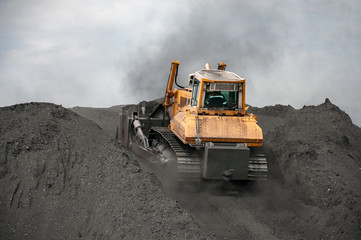 Obraz premium caterpillar tractor and travelling crane load black coal on supply field of thermoelectric power station