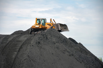 Obraz premium caterpillar tractor and travelling crane load black coal on supply field of thermoelectric power station