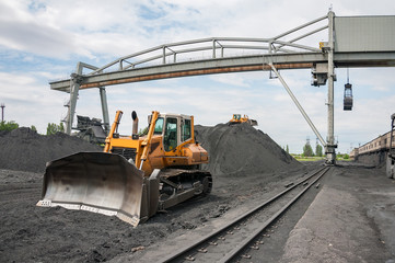 caterpillar tractor and travelling crane load black coal on supply field of thermoelectric power station