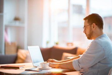 Young busy home office manager working with online data while sitting by desk in front of laptop