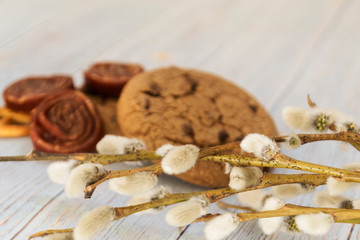 Oatmeal cookies and sweets. Willow branches on a wooden light background.