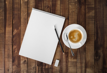 Obraz na płótnie Canvas Blank sketchbook, pencil, eraser and coffee cup on wood table background. Stationery elements. Template for placing your design. Flat lay.