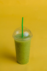 healthy detoxing cocktail from kiwi in glass with a straw. on the isolated yellow background. weight lose.