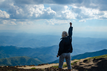 Woman with an arm raised as a sign of victory, on mountain top
