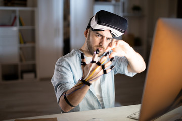 Businessman with vr headset on forehead looking at his fingers with sensors while checking their...