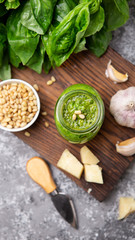 Pesto sauce in a bottle with ingredients (fresh basil, cheese, pine nuts, garlic)