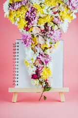 Easel with sketchbook and various flowers, spring or creativity concept