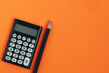 Calculator and pen on an orange background