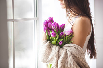 Unrecognizable young woman holding flowers indoors