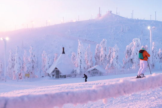 A group of skiers slide from the top of the mountain in the sun. Early morning. sunrise. Kuusamo Ruka. Finland. Panorama view.