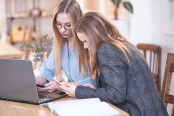 Naklejka premium two young women while working in the office, discuss workflow, or gossip about their colleagues. women entrepreneurs.
