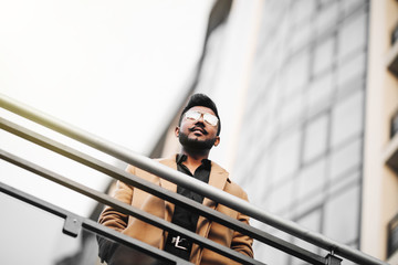 Low angle view of happy young indian businessman standing in front of office building