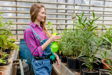 cheerful female using a spray bottle in gardening. close up side view photo.lifestyle concept. copy space