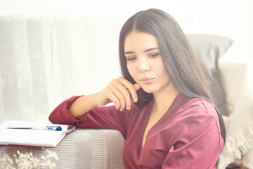 young girl sits on the floor in the early morning and writes in a diary or reads a book