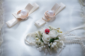 gold wedding rings on white silk cushion close up