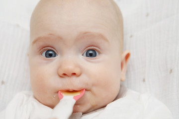 Beautiful Lovely five-month baby girl eating with a spoon. Healthy food. Maternal care. Childcare. Close-up.