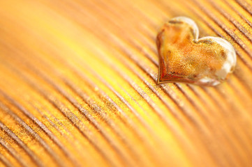 Shiny golden heart on gold background