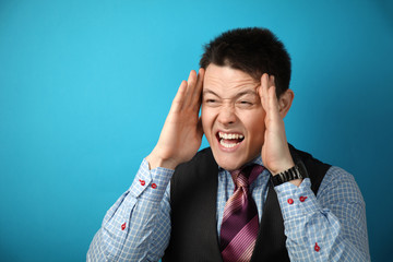 Young attractive businessman businessman in suit on blue background in rage, anger and madness.