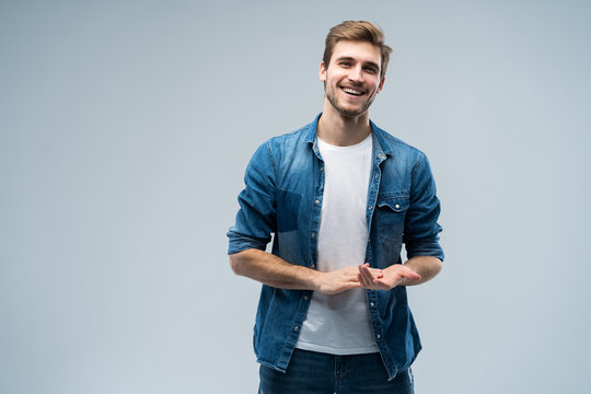 Portrait of stylish, stunning man in denim outfit standing over grey background.