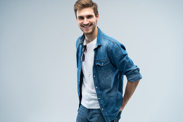 Fototapeta premium Portrait of stylish, stunning man in denim outfit standing over grey background.